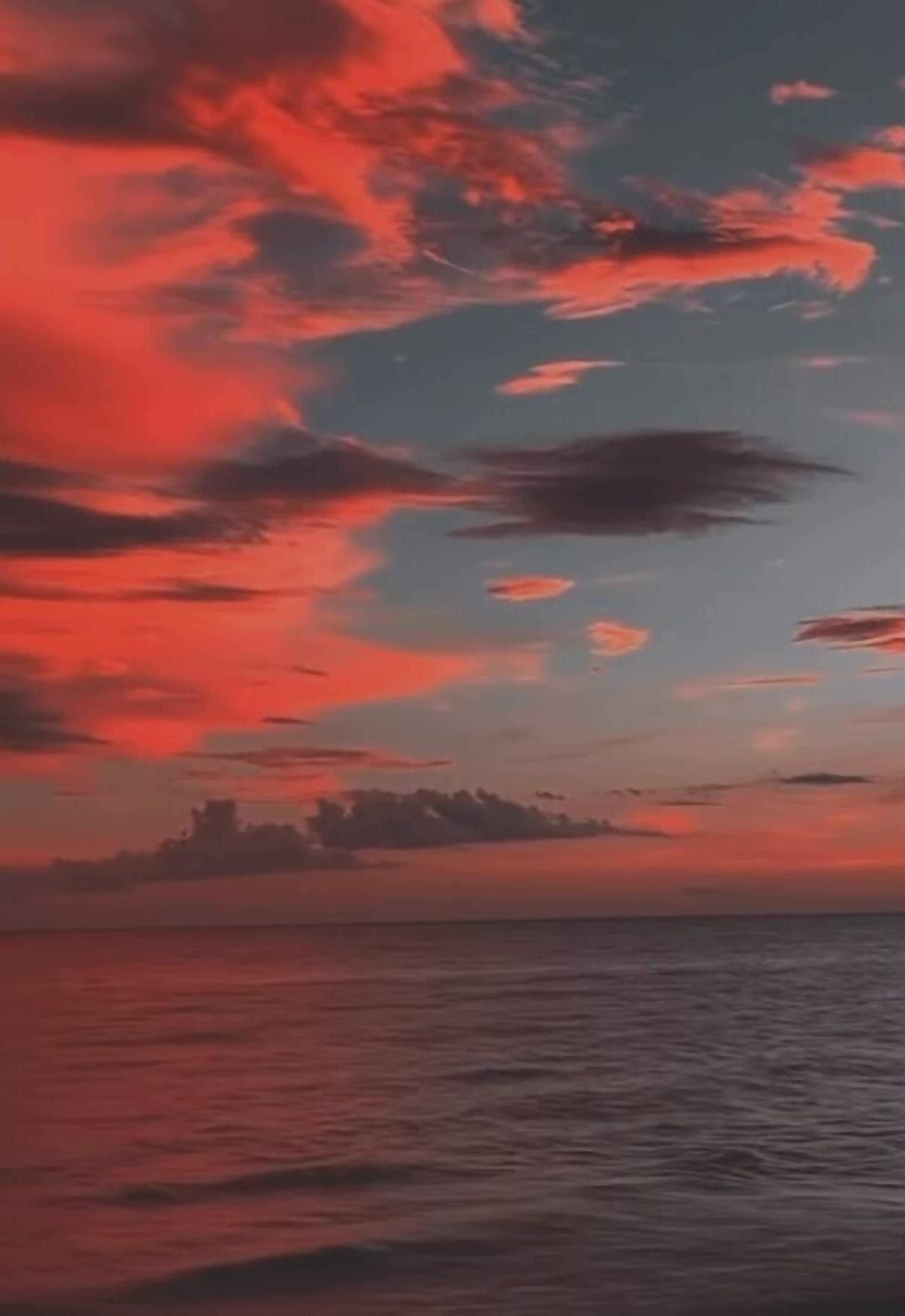 Solnedgang over et roligt hav med silhuetten af en fjerntliggende byhorisont.