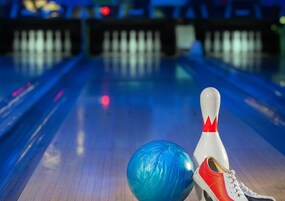 Una bolera con una bola de bolos azul y un bollo blanco con un triángulo rojo.