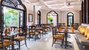 A spacious dining area with multiple tables and chairs, large windows with arched tops, and a checkered floor pattern. - Little Residence. A Boutique Hotel & Spa (Da Nang)