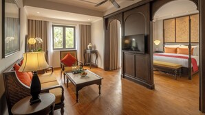 A hotel room with a large bed, a TV, a ceiling fan, a seating area with a table, and a view of the outdoors. - Little Residence. A Boutique Hotel & Spa (Da Nang)