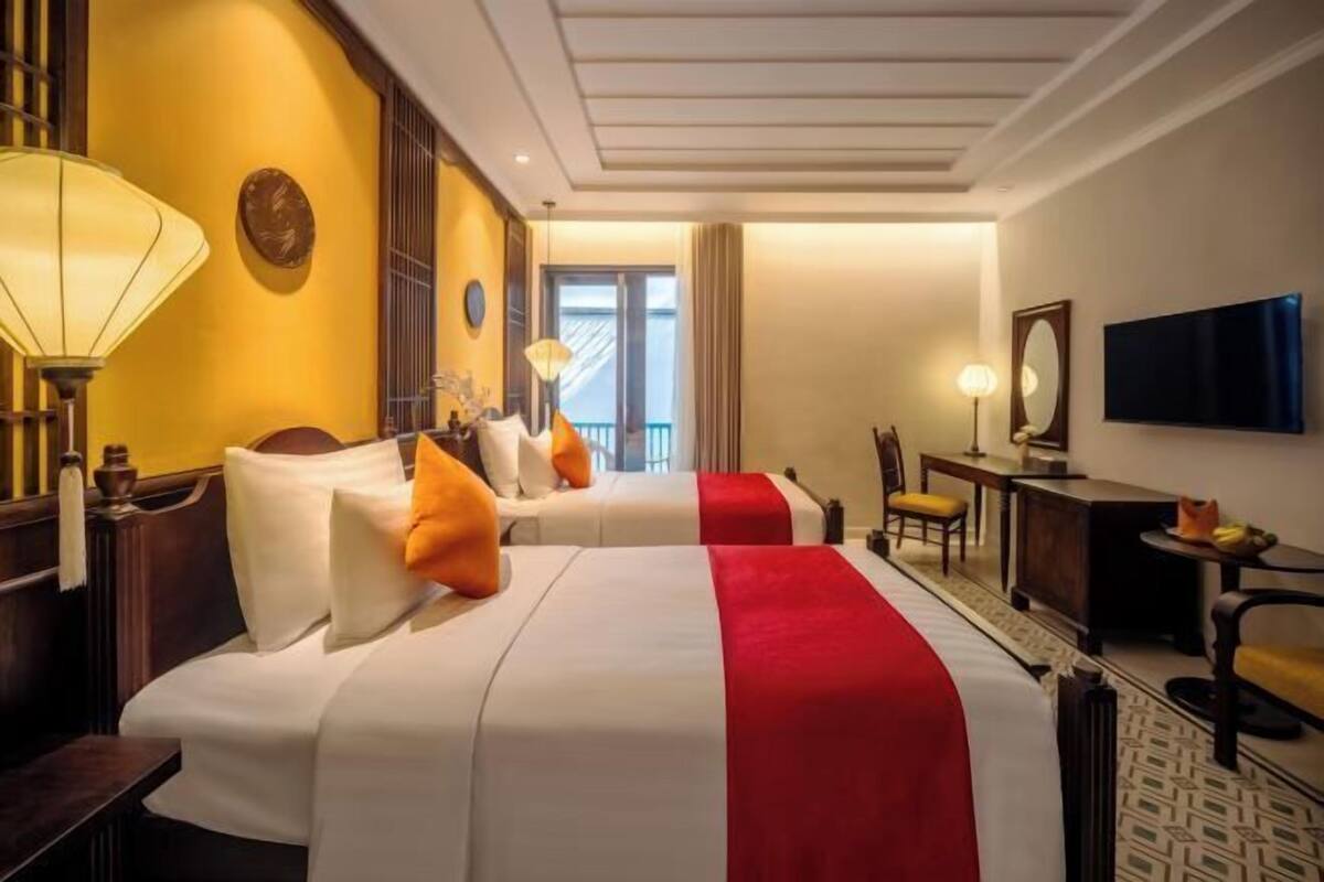 A hotel room with two beds, a television, a desk, and a chair.