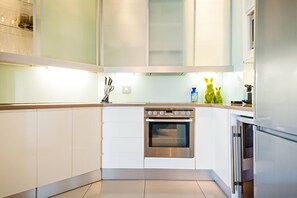A modern kitchen with white cabinets, a stainless steel oven, and a refrigerator. - 512 The Granger (Cape Town)