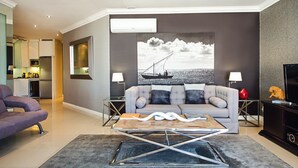 A modern living room with a grey sofa, a coffee table, and a large wall-mounted TV. - 512 The Granger (Cape Town)