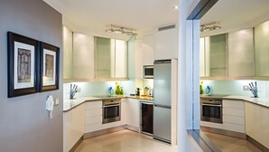 A modern kitchen with white cabinets, stainless steel appliances, and a tiled floor. - 512 The Granger (Cape Town)