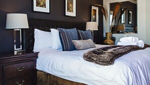 A bedroom with a large bed, dark walls, and framed artwork. - 512 The Granger (Cape Town)