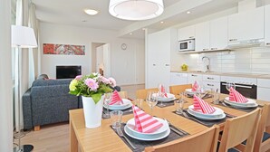 A modern dining area with a wooden table set for four, white cabinets, and a flat-screen TV in the background. - Forenom Serviced Apartments Tampere Pyynikki (Tampere)