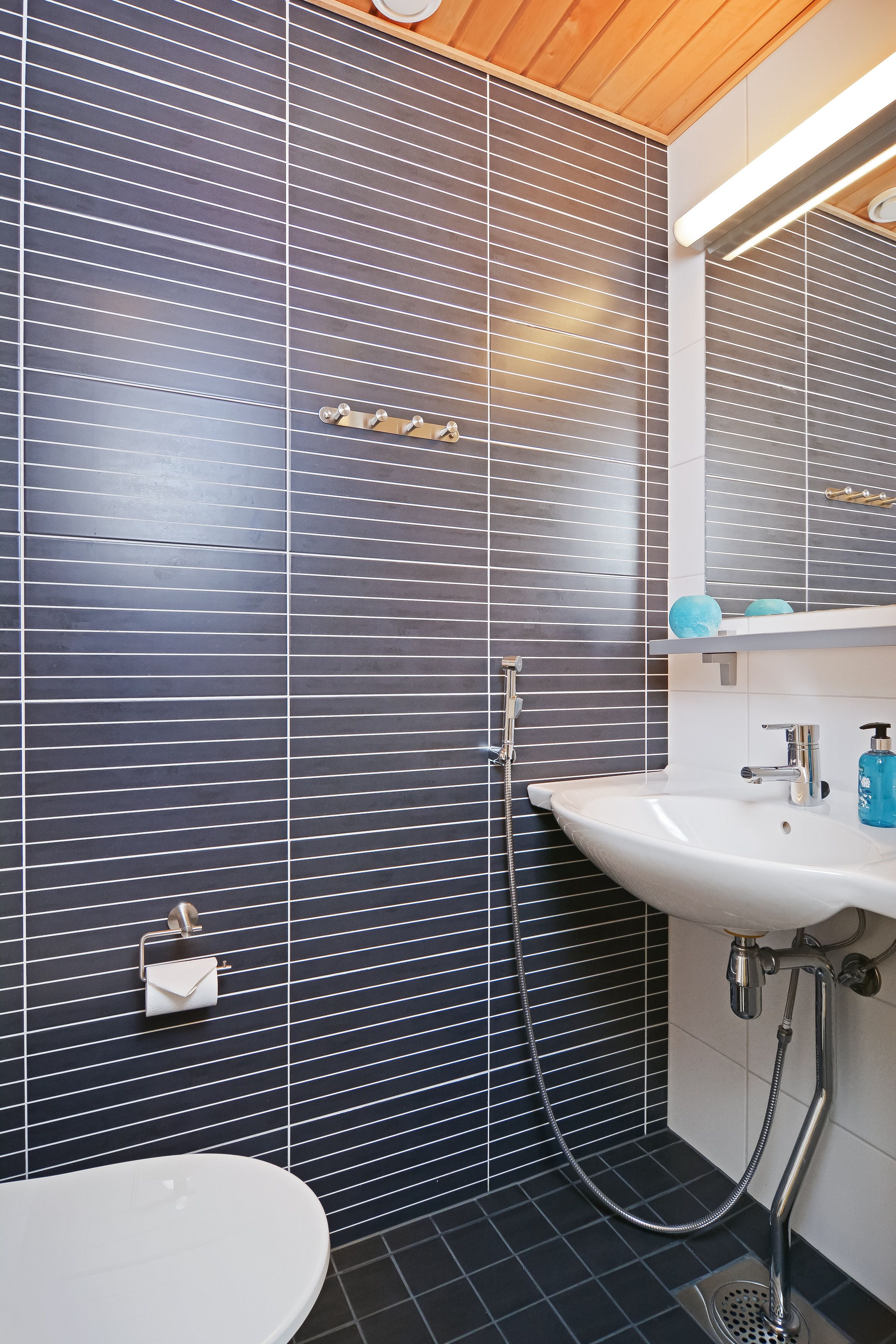 Une salle de bain avec un lavabo blanc, un miroir et une douche.