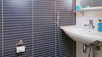 Une salle de bain avec un lavabo blanc, un miroir et une douche.