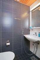 Ein Badezimmer mit einem weißen Waschbecken, einem Spiegel und einer Dusche.