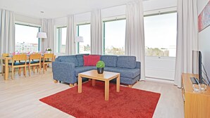 A modern living room with a blue sofa, wooden dining table, and red rug. - Forenom Serviced Apartments Tampere Pyynikki (Tampere)