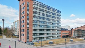 A multi-story building with a mix of brick and glass facades, a visible entrance, and a clear sky. - Forenom Serviced Apartments Tampere Pyynikki (Tampere)