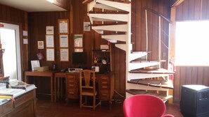 Une pièce dotée d’un escalier en colimaçon, de murs en bois, d’un bureau avec un ordinateur et de divers certificats accrochés au mur.