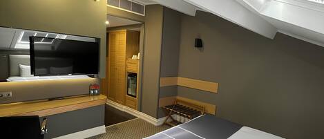 A hotel room with a bed, a desk, a chair, a TV, and a wardrobe.