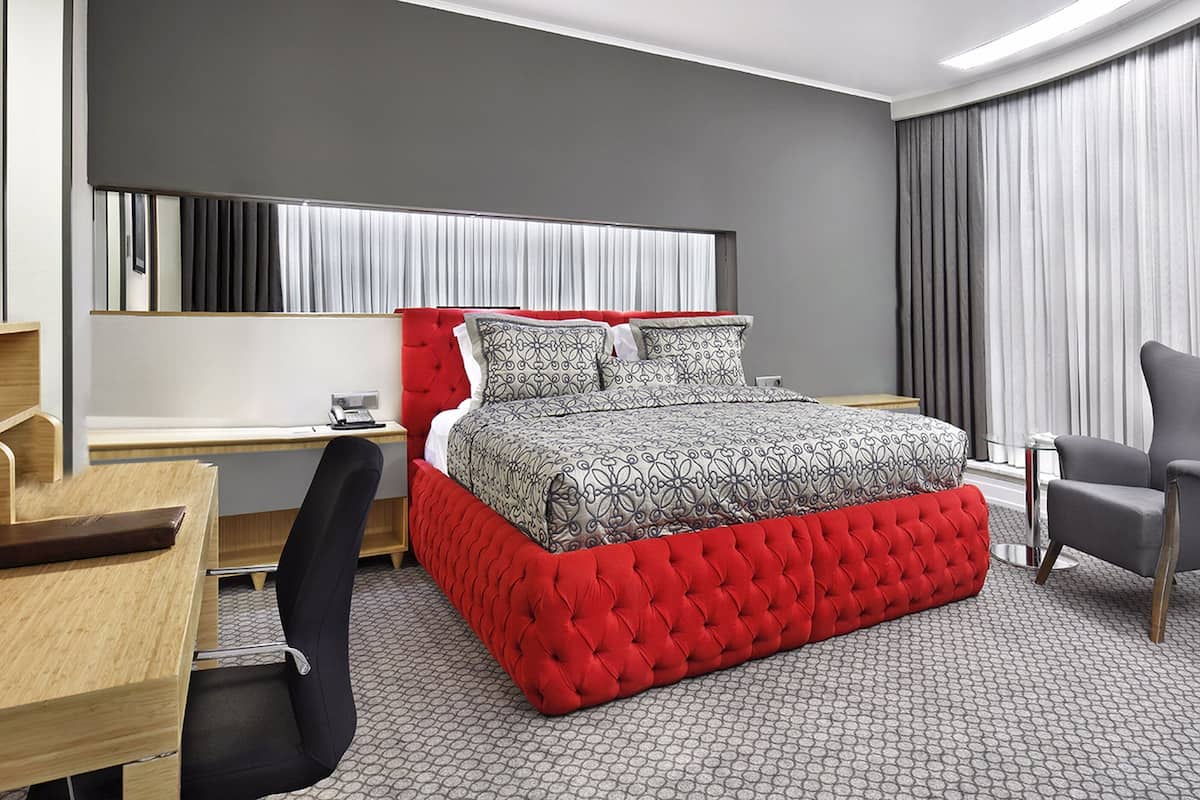 Une chambre d’hôtel moderne équipée d’un grand lit, d’un bureau, d’une chaise et d’un téléviseur.