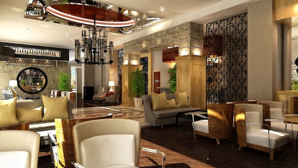 Eine großzügige Lobby mit hoher Decke, einem zentralen Kronleuchter und einer Sitzecke mit mehreren Stühlen und Sofas.