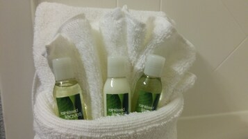 A white towel with three bottles of 'rainkissed leaves' in a bathroom setting.