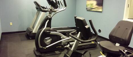A gym with stationary bikes, an elliptical, and a rowing machine.