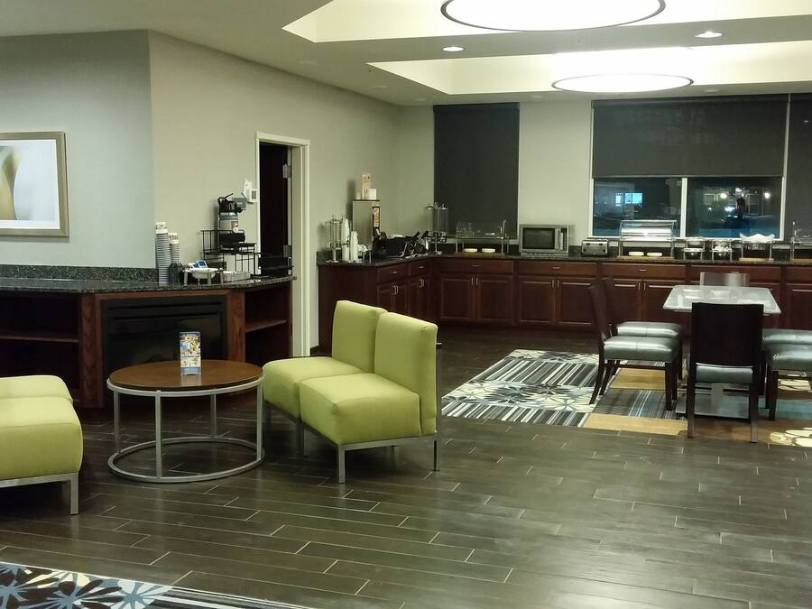 Una cocina moderna con armarios de madera oscura, un comedor con mesa y sillas, y una sala de estar con sofá y sillones.
