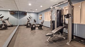 A gym with exercise equipment, a bench, and a wall-mounted TV.