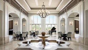Un hall d’entrée spacieux, agrémenté d’un magnifique lustre, d’une fontaine et d’un piano à queue.