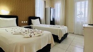 A hotel room with two beds, a minibar, a TV, and a large window with curtains. - The Green Valley Hotel (Fethiye)
