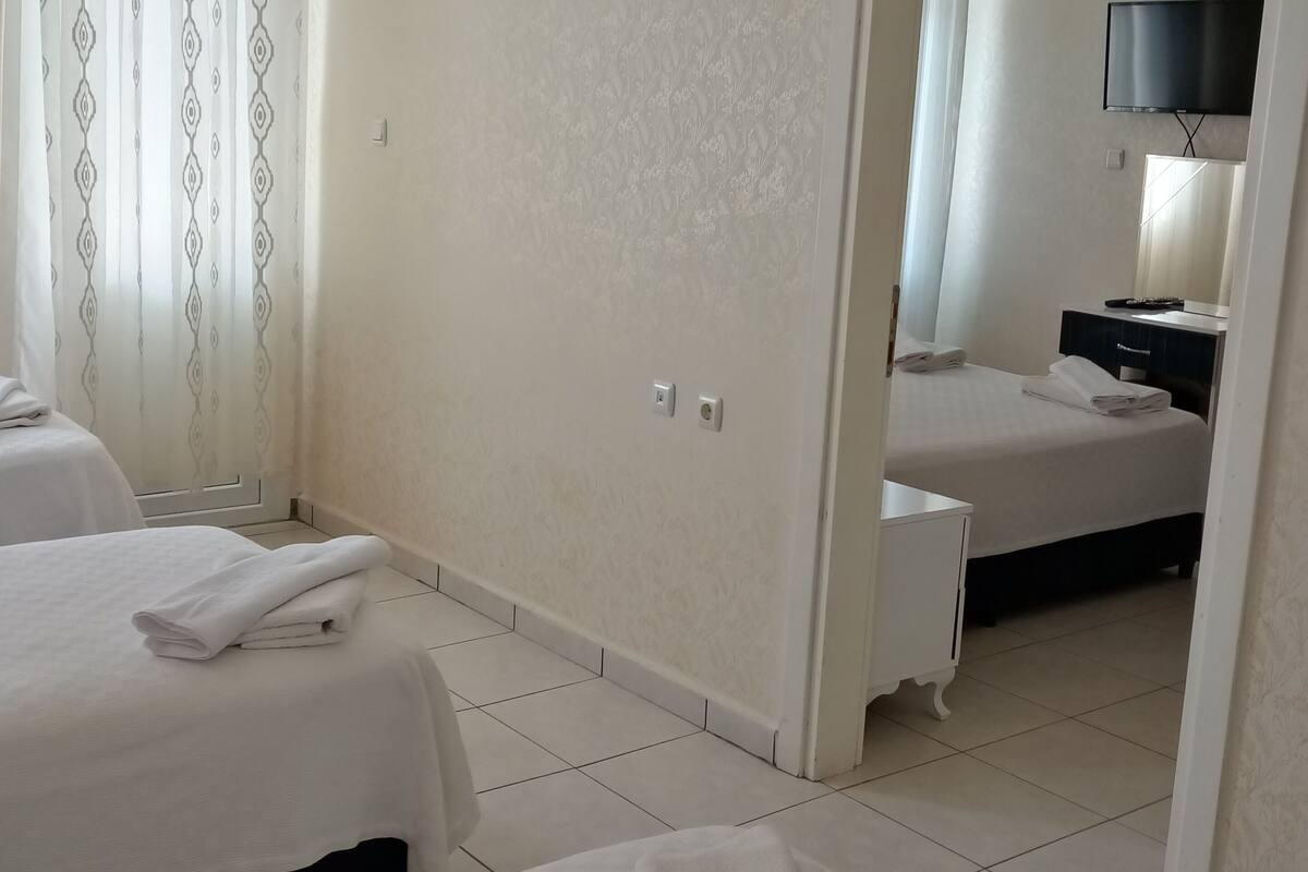 A hotel room with two beds, a TV, and a bathroom visible through an open door.