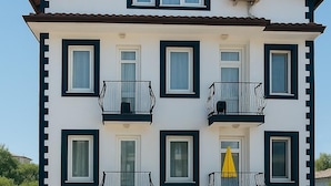 A multi-story building with balconies, a central air conditioning unit, and a yellow umbrella on one balcony. - The Green Valley Hotel (Fethiye)