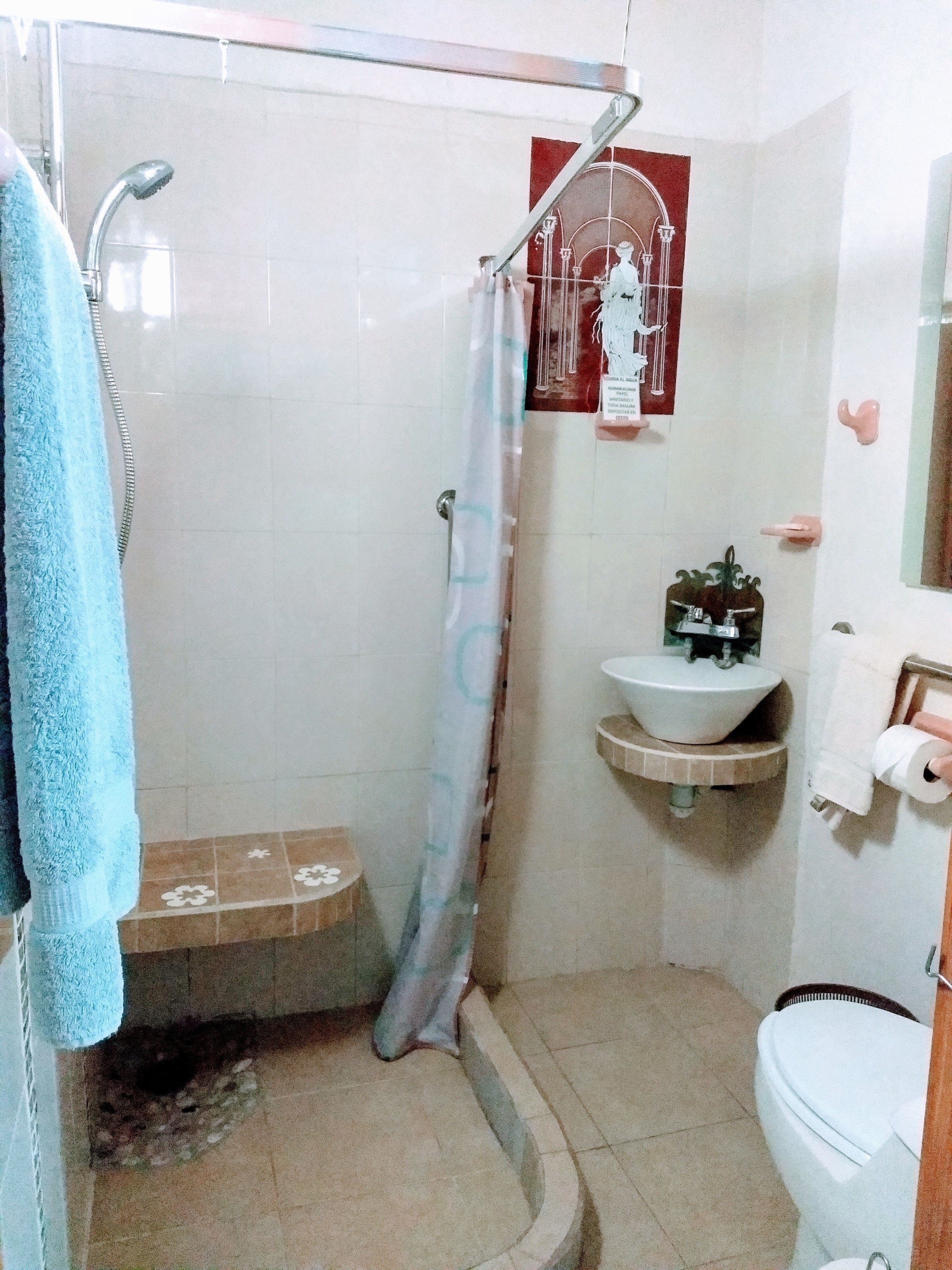 Ein Badezimmer mit Dusche, Toilette, Waschbecken und Handtuchhalter.