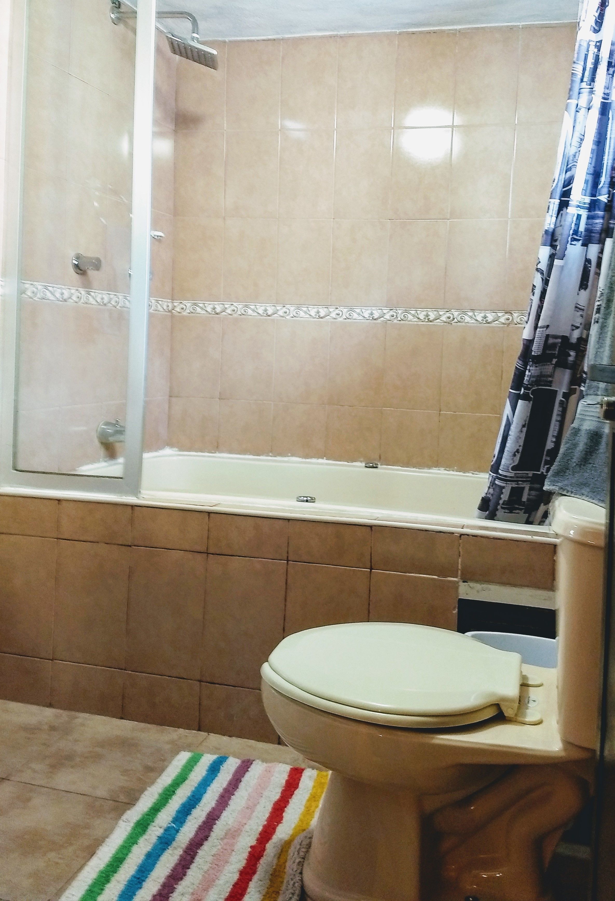 A bathroom with a bathtub, toilet, and shower area.