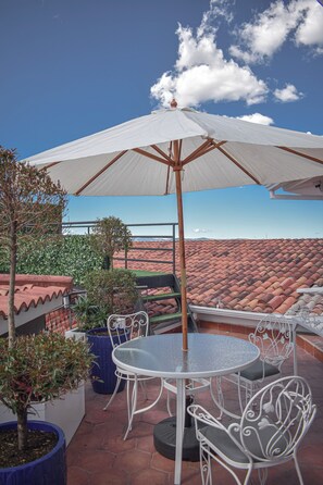 A patio with a round table and chairs, an umbrella, and potted plants. - Parc Royale Suites Hotel (Cuenca)