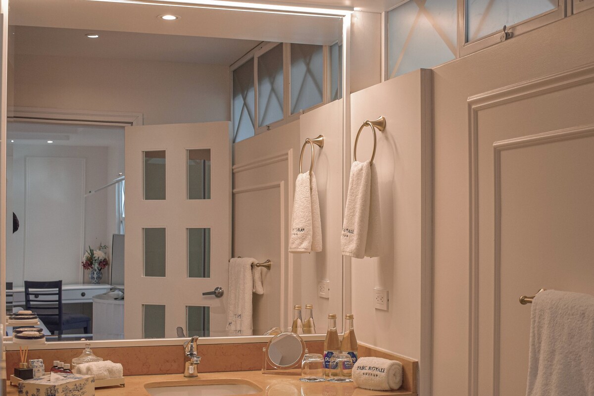 A bathroom with a large mirror, a sink, and a towel rack.