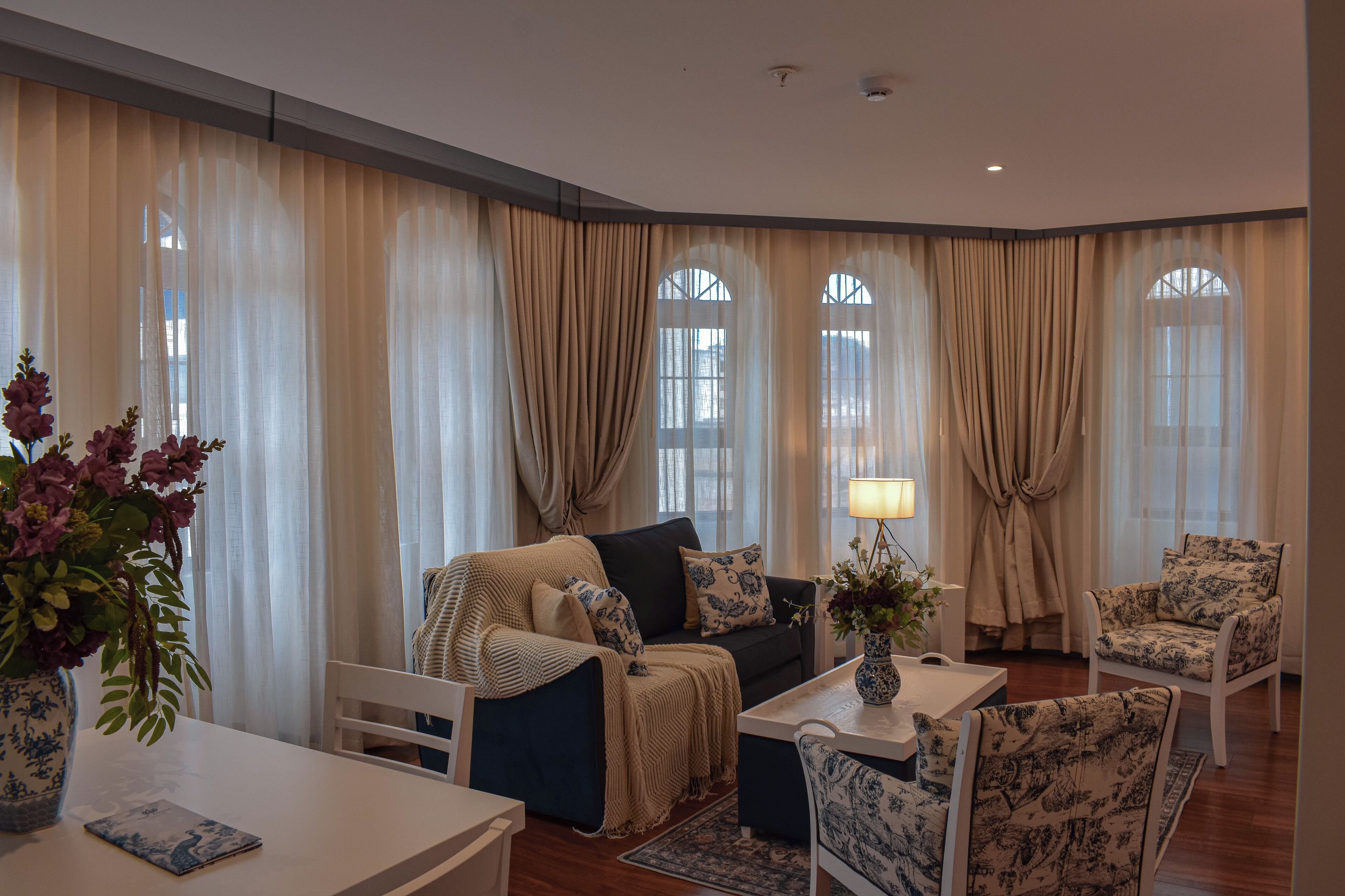Ein Wohnzimmer mit einer Couch, Sesseln, einem Couchtisch und einer Lampe.