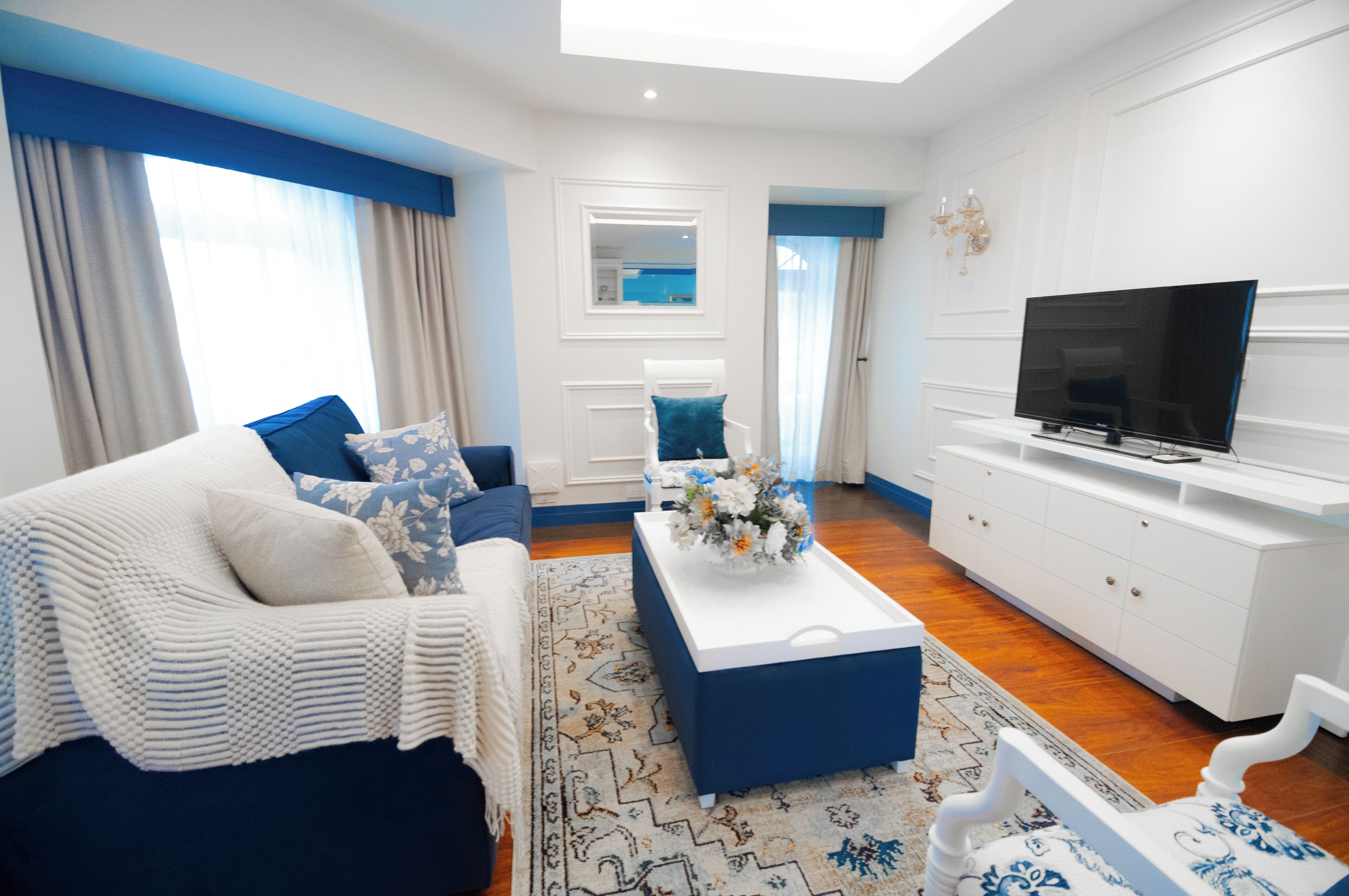 Una sala de estar moderna con sofá, mesa de centro, televisor y un mueble blanco.