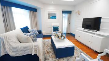 Una sala de estar moderna con sofá, mesa de centro, televisor y un mueble blanco.