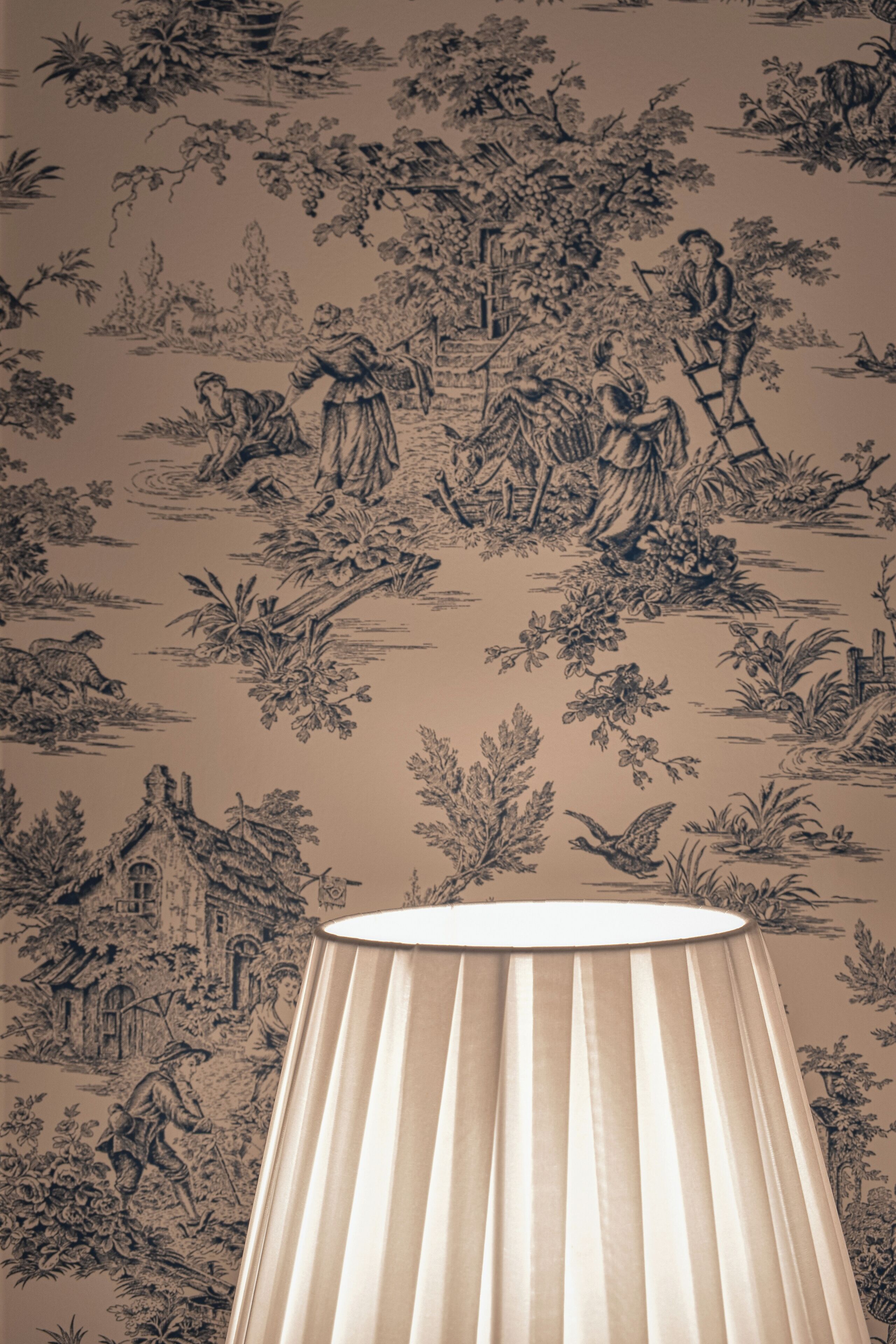 A room with a patterned wallpaper, a lamp, and a window.