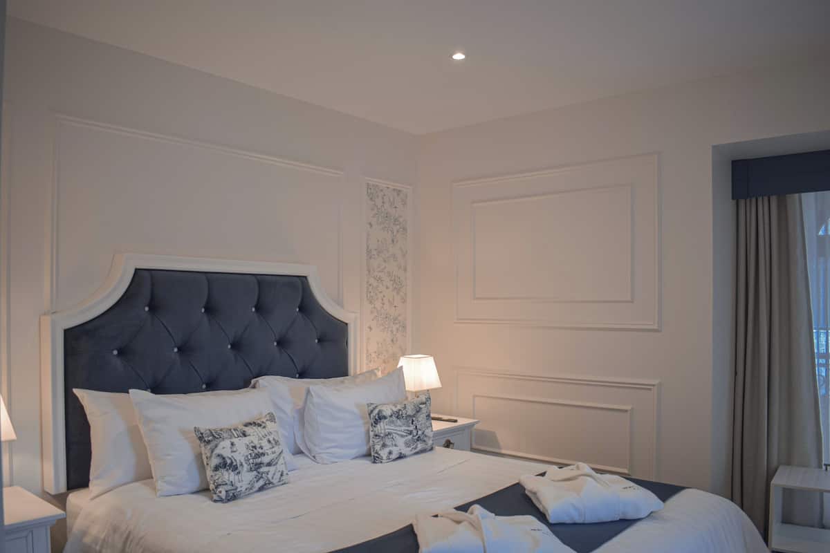 A neatly arranged bedroom with a large bed, bedside tables, and a lamp.