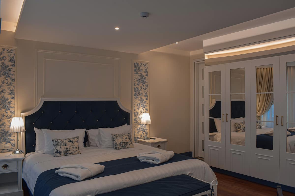 A bedroom with a large bed, bedside tables, a wardrobe, and a mirror.