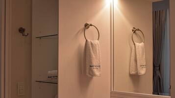 A bathroom with a large mirror, a sink, and two towels hanging on the wall.