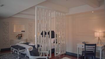 Un dormitorio con cama, escritorio, silla, lámpara y un biombo decorativo.