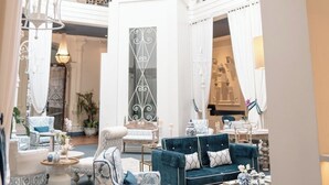 A spacious, elegantly decorated interior with a high ceiling, ornate metal railings, and a variety of seating arrangements including patterned sofas and armchairs. - Parc Royale Suites Hotel (Cuenca)