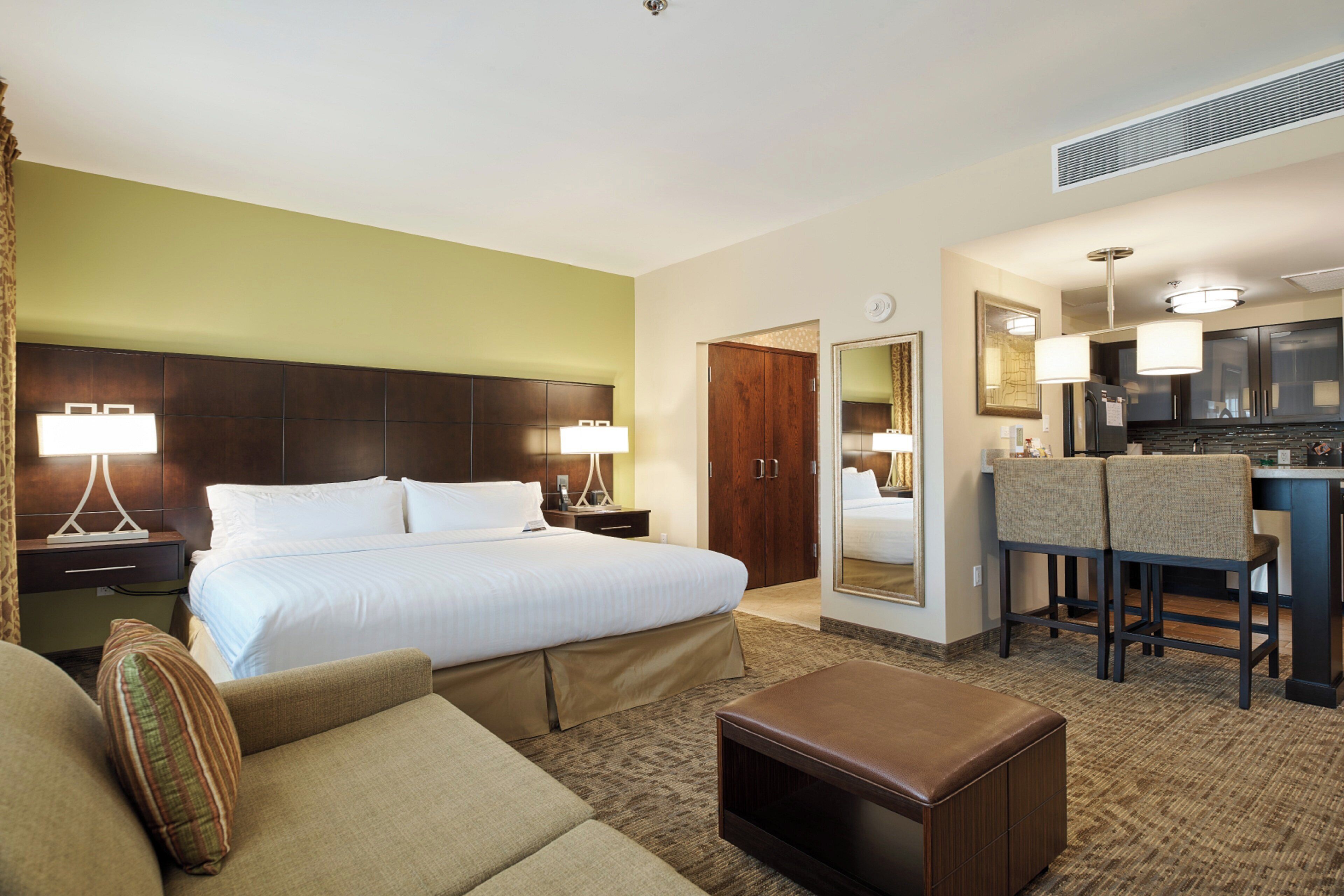 Een hotelkamer met een groot bed, nachtkastjes, een zithoek, een klein tafeltje en een kitchenette.