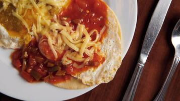 A plate with a sandwich, tomato sauce, and shredded cheese.