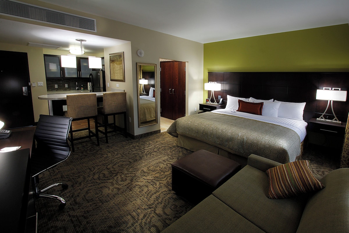 Een hotelkamer met een bed, een bureau, een stoel, een bank en een spiegel.