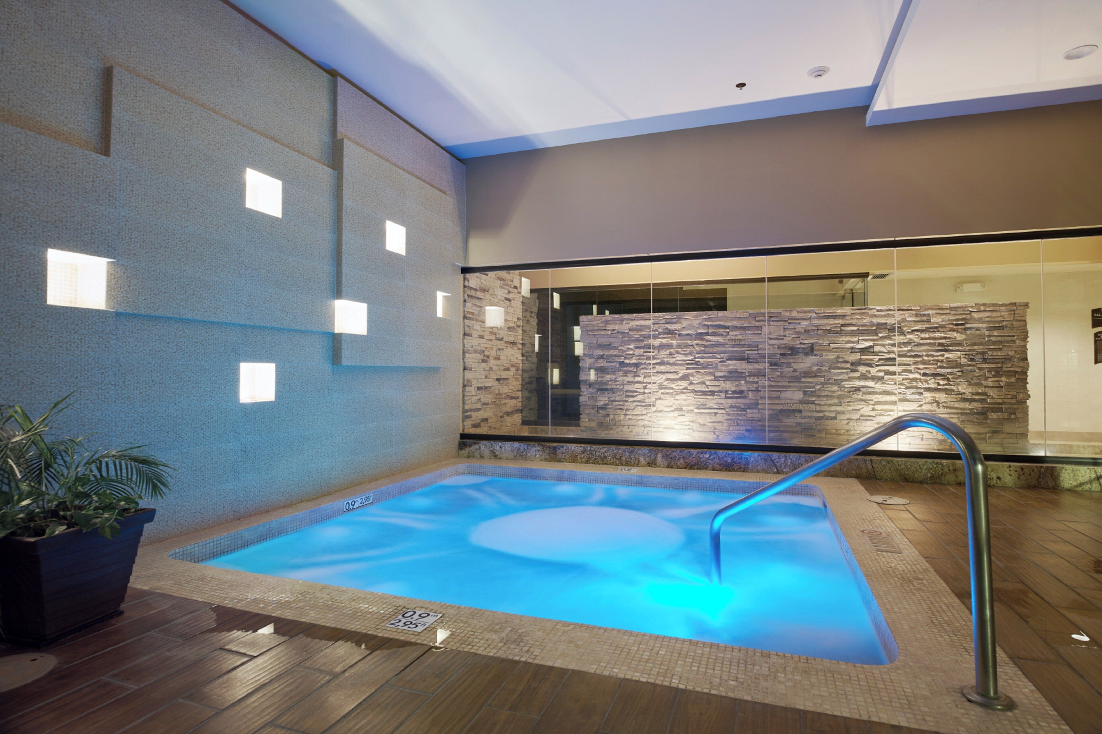 A hot tub with a stone wall backdrop and a wooden floor.