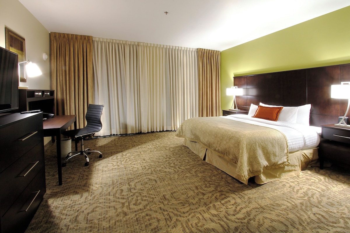 Een hotelkamer met een bed, een bureau, een stoel, een televisie en een lamp.