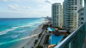 Un hotel frente a la playa con piscina, vistas al océano y varios edificios de gran altura.