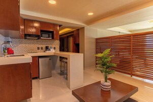 A modern kitchen with wooden cabinets, a microwave, and a sink. There is a small island with a plant.