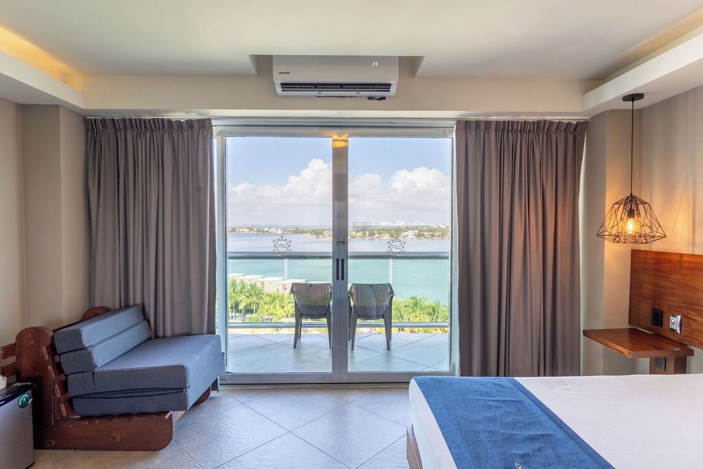 Habitación de hotel con balcón, cama, sofá y escritorio.