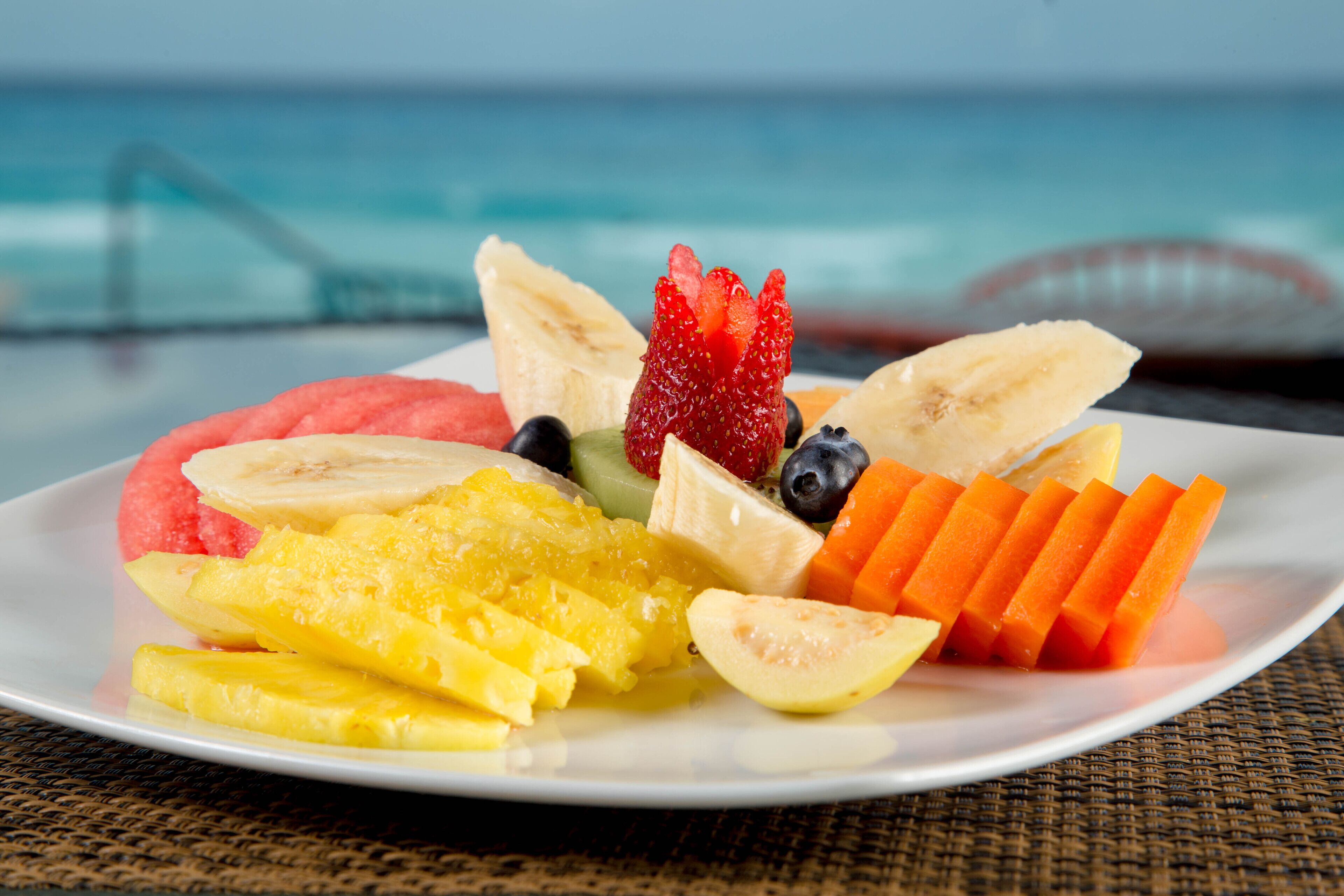 Ein Teller mit einer Auswahl an Früchten, darunter Erdbeeren, Bananen, Blaubeeren, Ananas und Wassermelone.