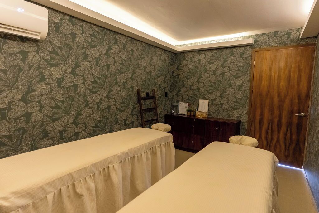 A room with two beds, a wooden wardrobe, a mirror, and a wall-mounted air conditioner.